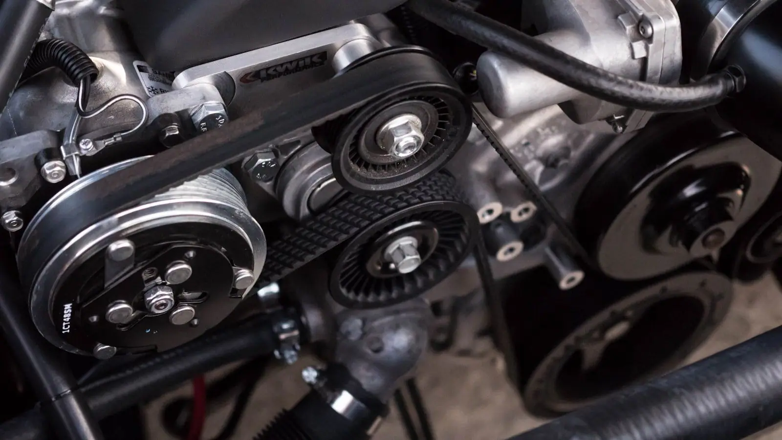 Close-up of an engine bay showing belts, pulleys and polished aluminium components