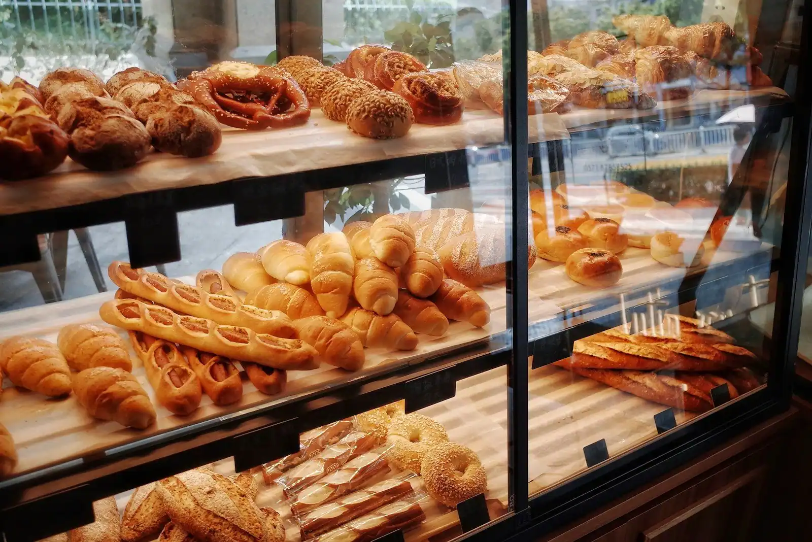 Bakery display case with shelves of bread, rolls, croissants and pastries.