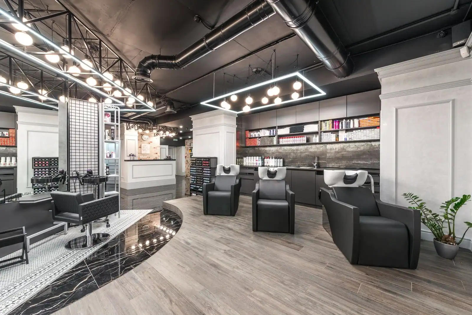 Backwash chairs and sinks beside a potted plant in the bright, contemporary salon