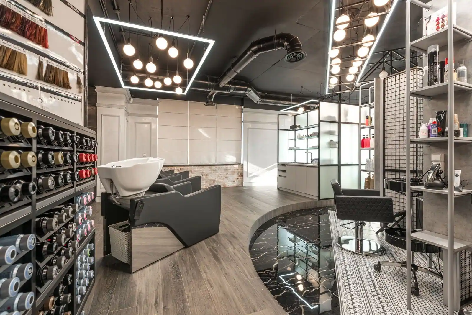 Black backwash chair and white sink in the modern salon, with bright glowing lamps