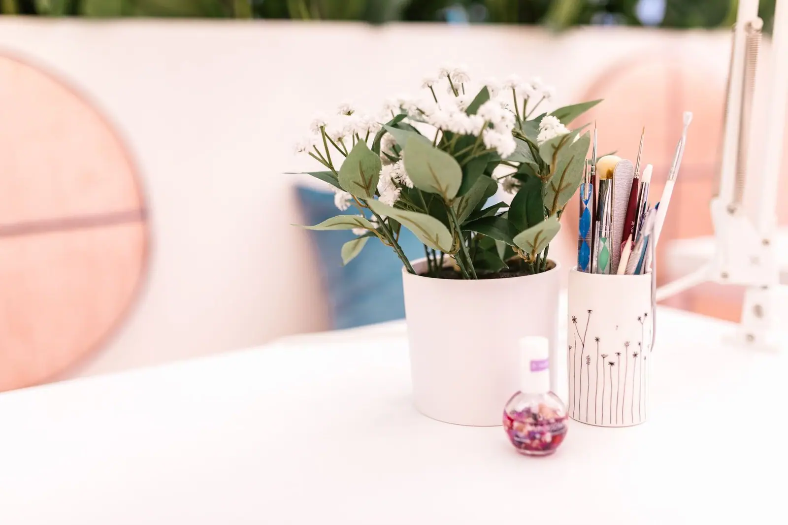Nail polish bottle and a white planter of green leaves on the nail salon countertop